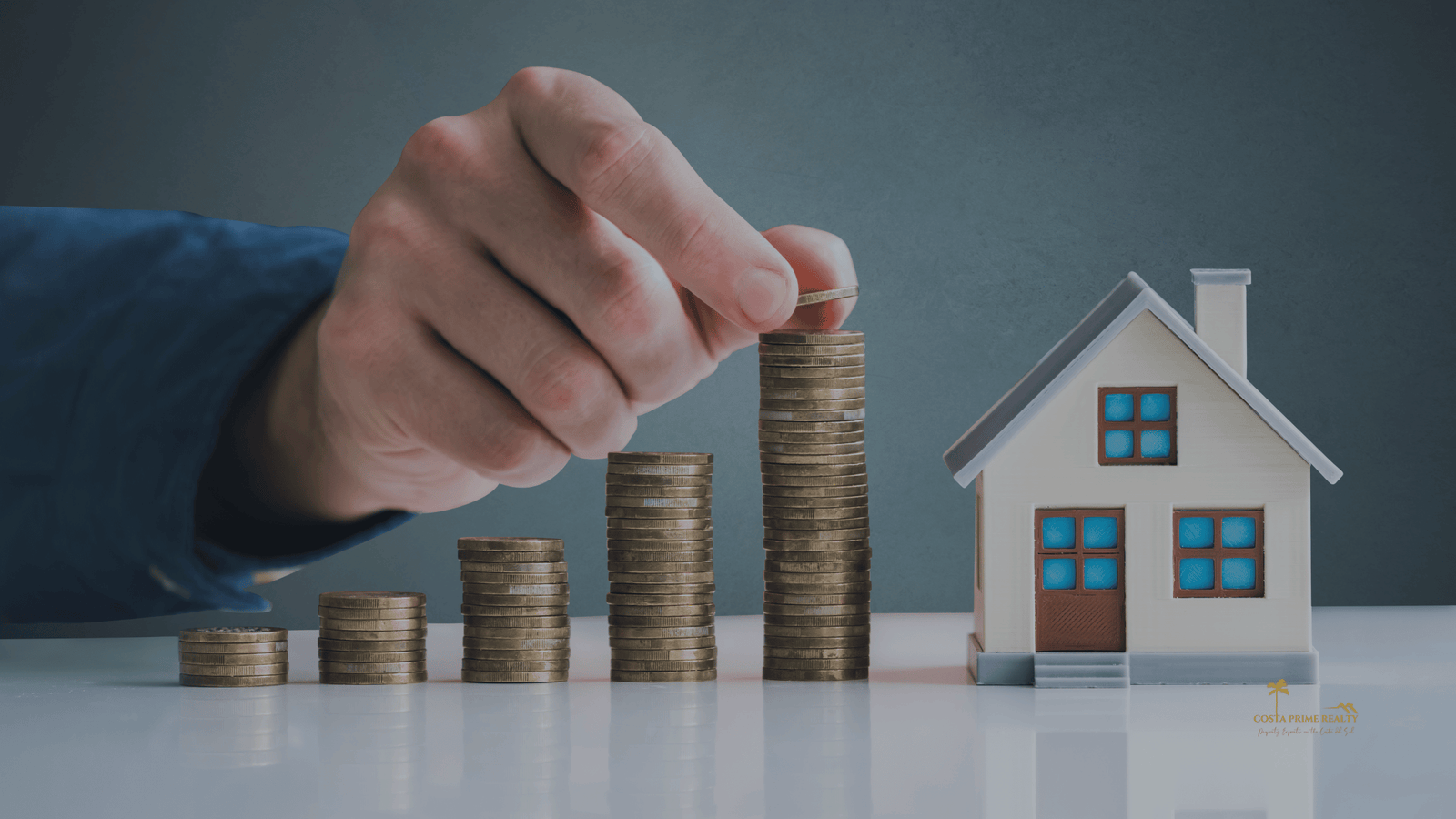Coins stacked next to a small house model representing financing when buying property in Spain